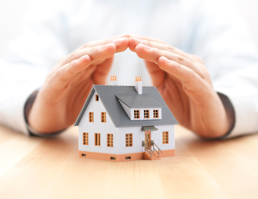 hands over a small house protecting it - How Insulation Can Protect Your Home in New Orleans