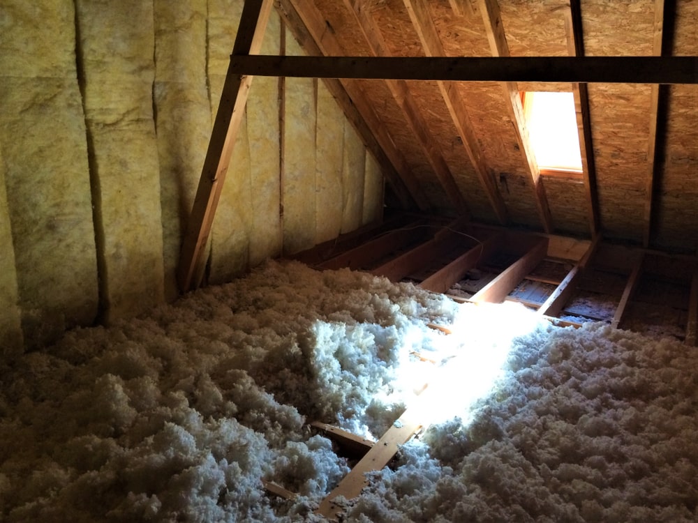 Close-up view of blown in fiberglass insulation filling the spaces between the joists in a home's attic.