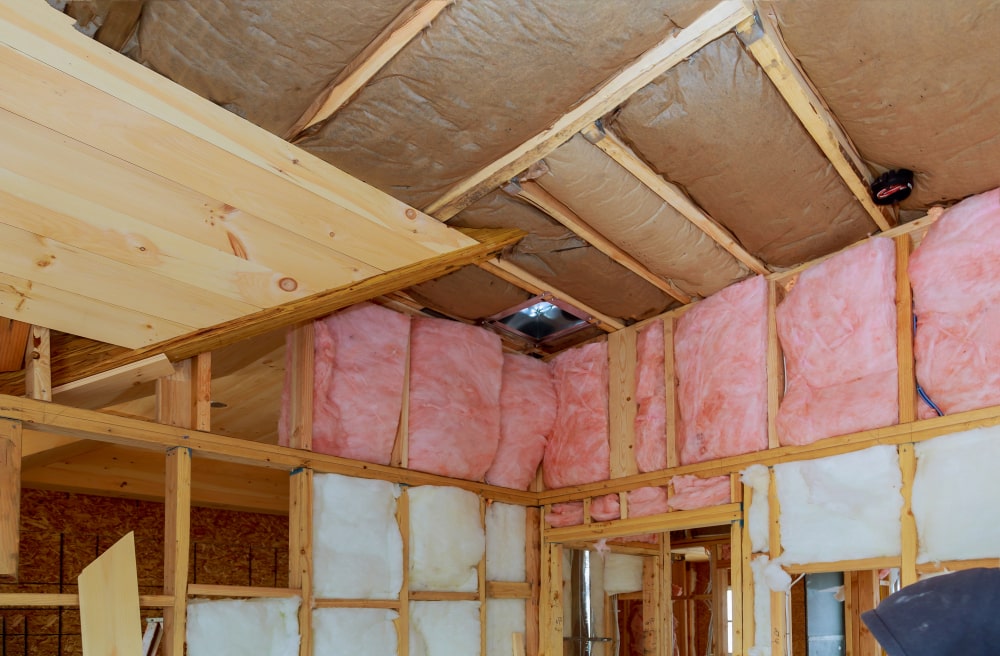 Mineral glass wool insulation fitted within a wooden frame on an inclined wall, positioned close to the wooden ceiling, demonstrating effective insulation techniques in a New Orleans home.